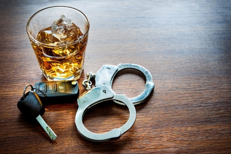 Glass of alcohol with keys next to it.