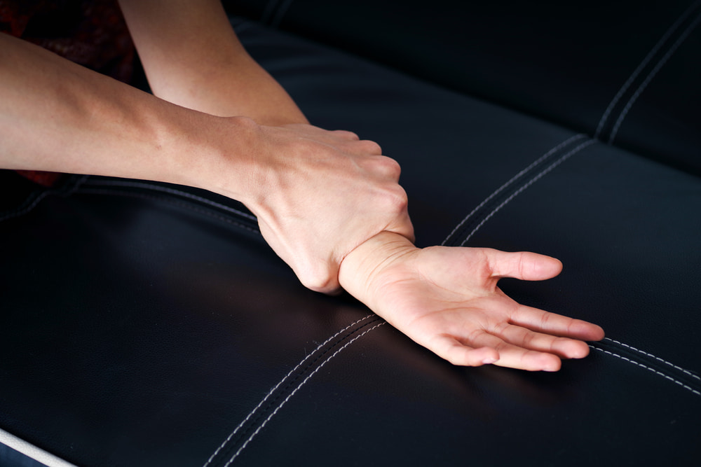 Hand pinning a person's wrist down on a couch during an assault
